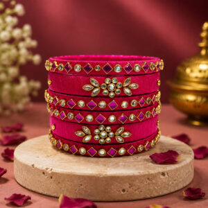 Royal pink floral silk thread bangles displayed with traditional decor